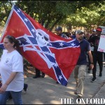 A woman carrying a Mississippi state flag is followed by those calling on the University of Mississippi to remove the Mississippi state flag from university grounds, in Oxford, Miss. on Friday, October 16, 2015.